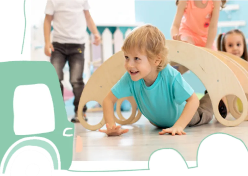 A young child in an aqua top crawls under a wooden climbing arch while friends play at Fun Street soft play